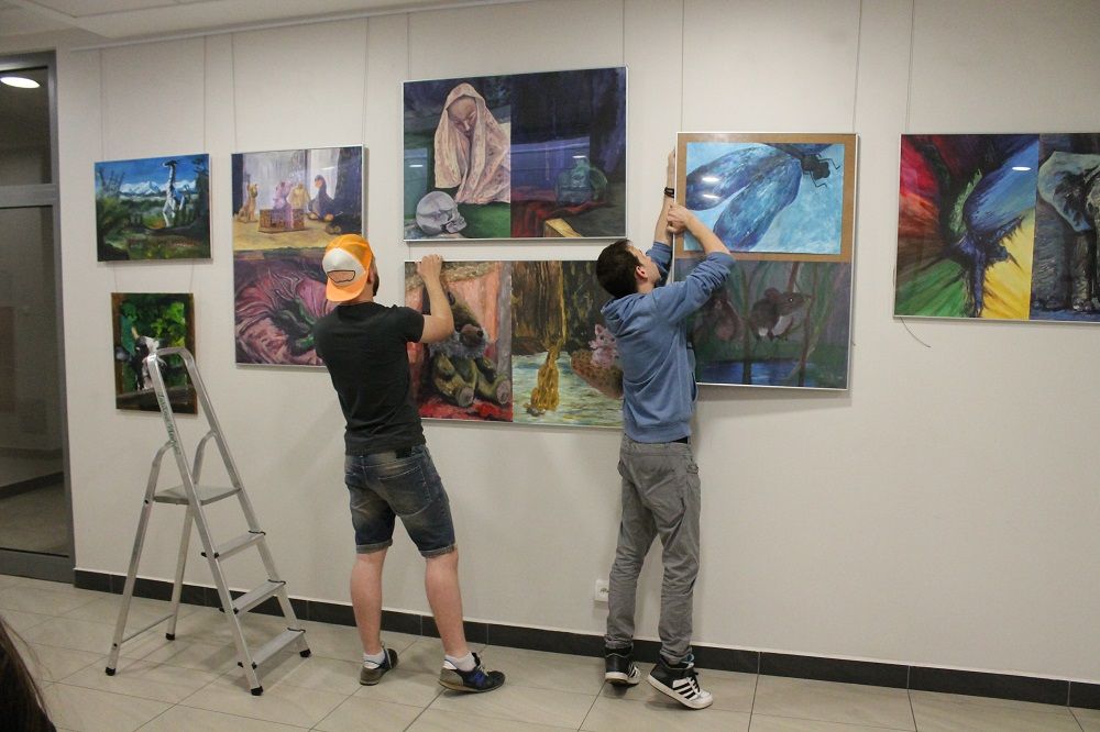 Studenci montują prace na ścianie galerii